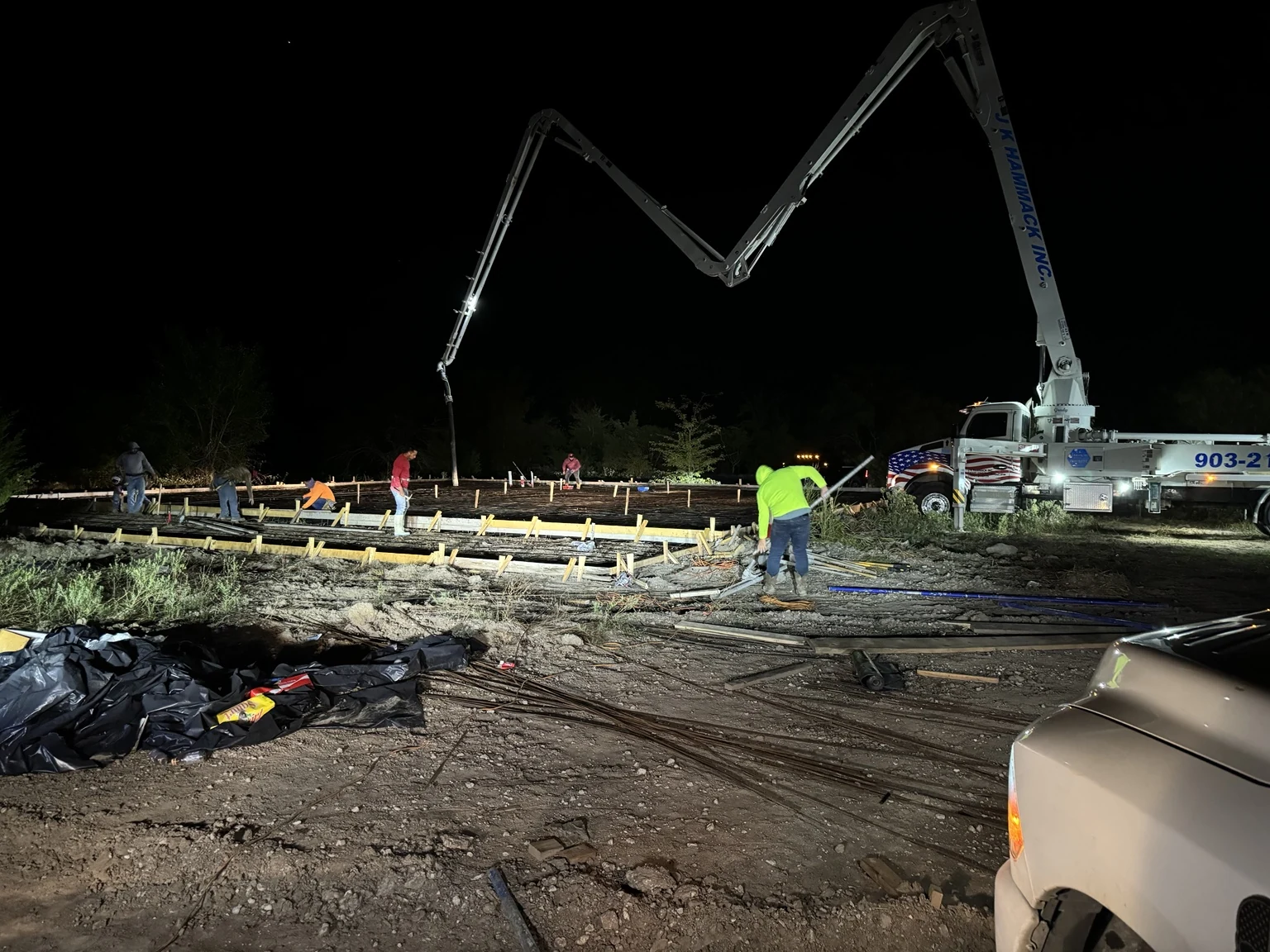 Concrete crew and boom pump at work after dark